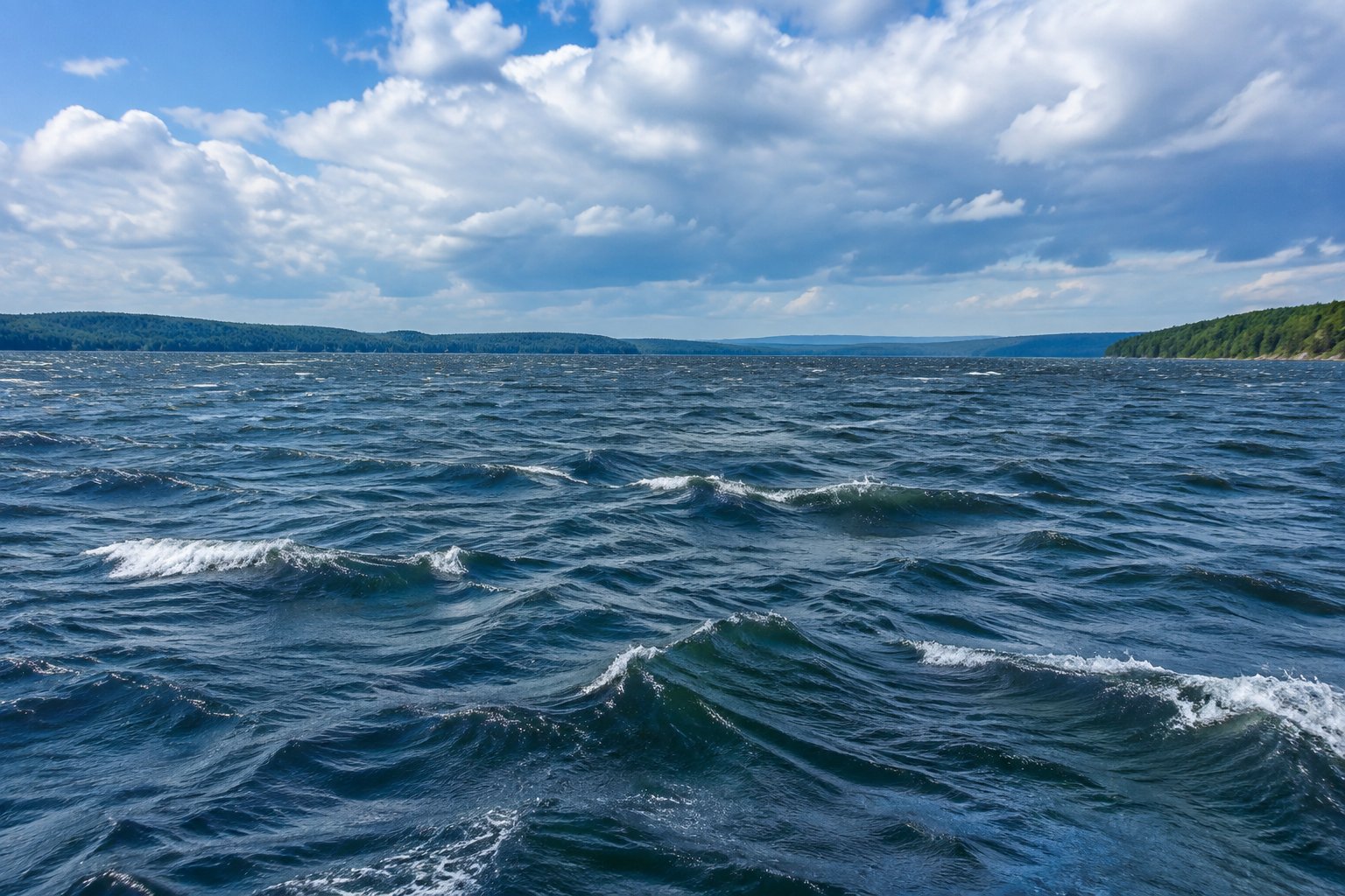Rough wind-churned water with whitecaps on Lake of the Ozarks, bordered by wooded hills beneath a cloudy sky.